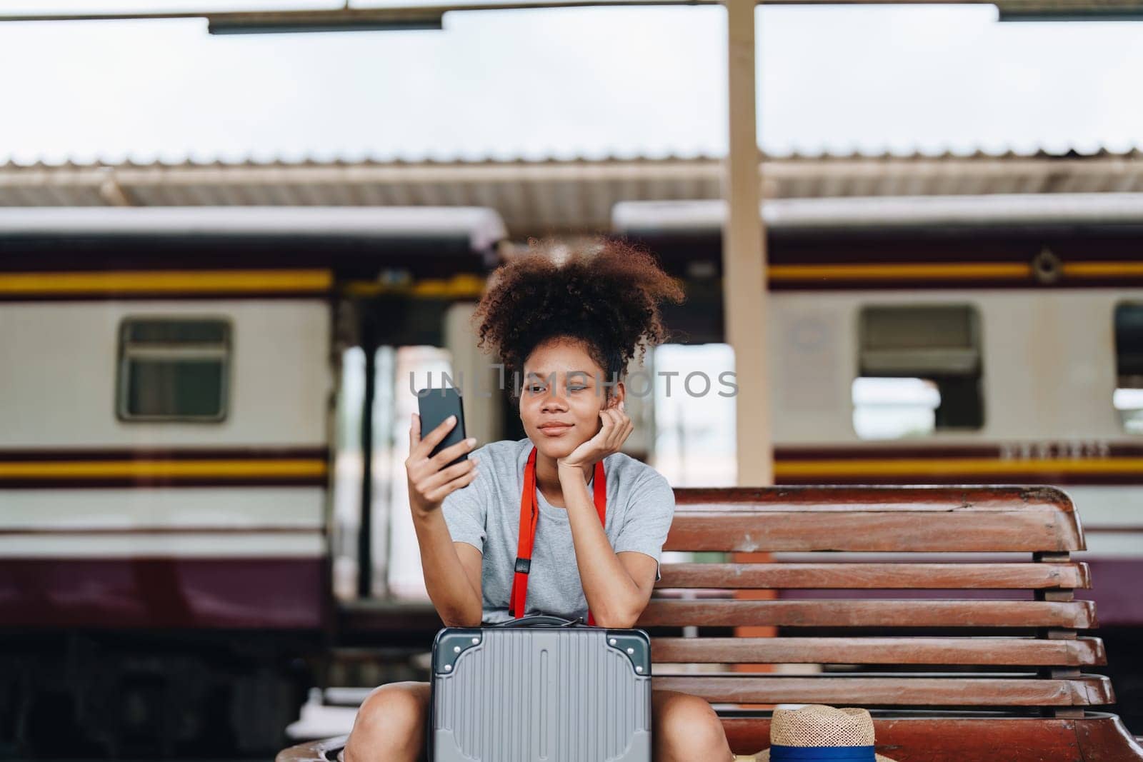 Asian teenage girl african american traveling using smartphone moblie while waiting for a train at a station