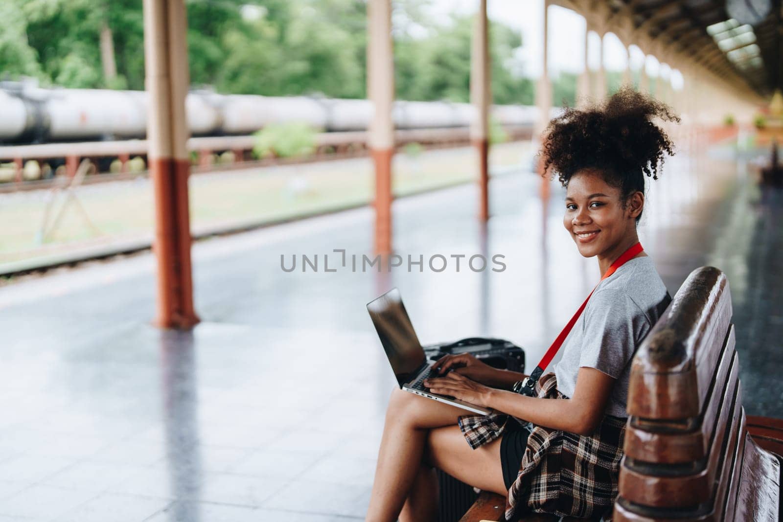 Asian teenage girl african american traveling using computer laptop while waiting for a train at a station