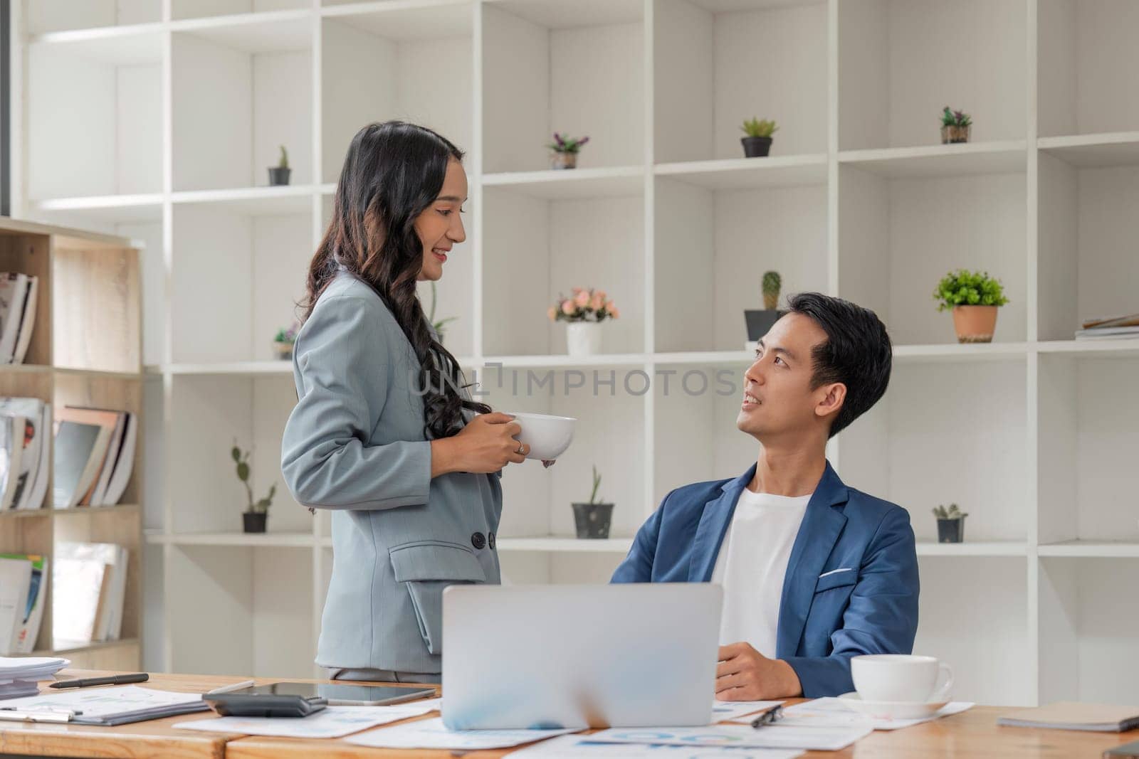 Two business people talk project strategy at office meeting room. Businessman discuss project planning with colleague at workplace while having conversation and advice on financial data report.