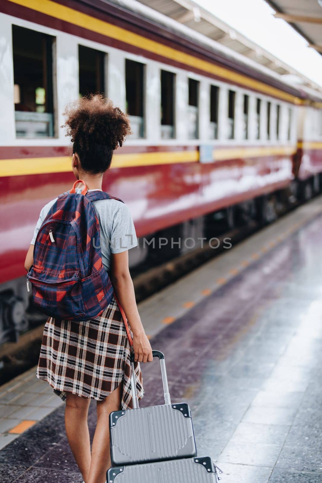 Tourists african american are showing happy expressions while waiting for their journey in the train station. by Manastrong