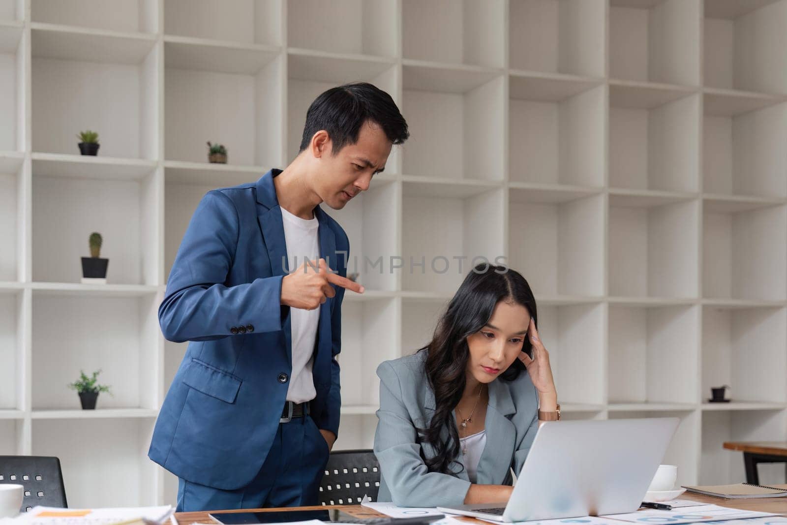 Two business people being stressed while working on a laptop in an office, Business partners working together, Collaborating teamwork analyzing paperwork data, business reports.