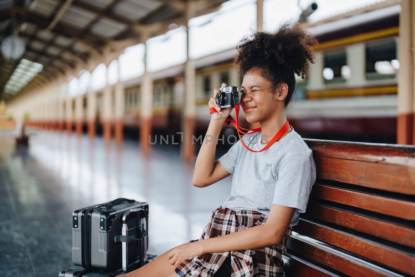 Asian teenage girl african american traveling using a camera take a photo to capture memories while waiting for a train at the station