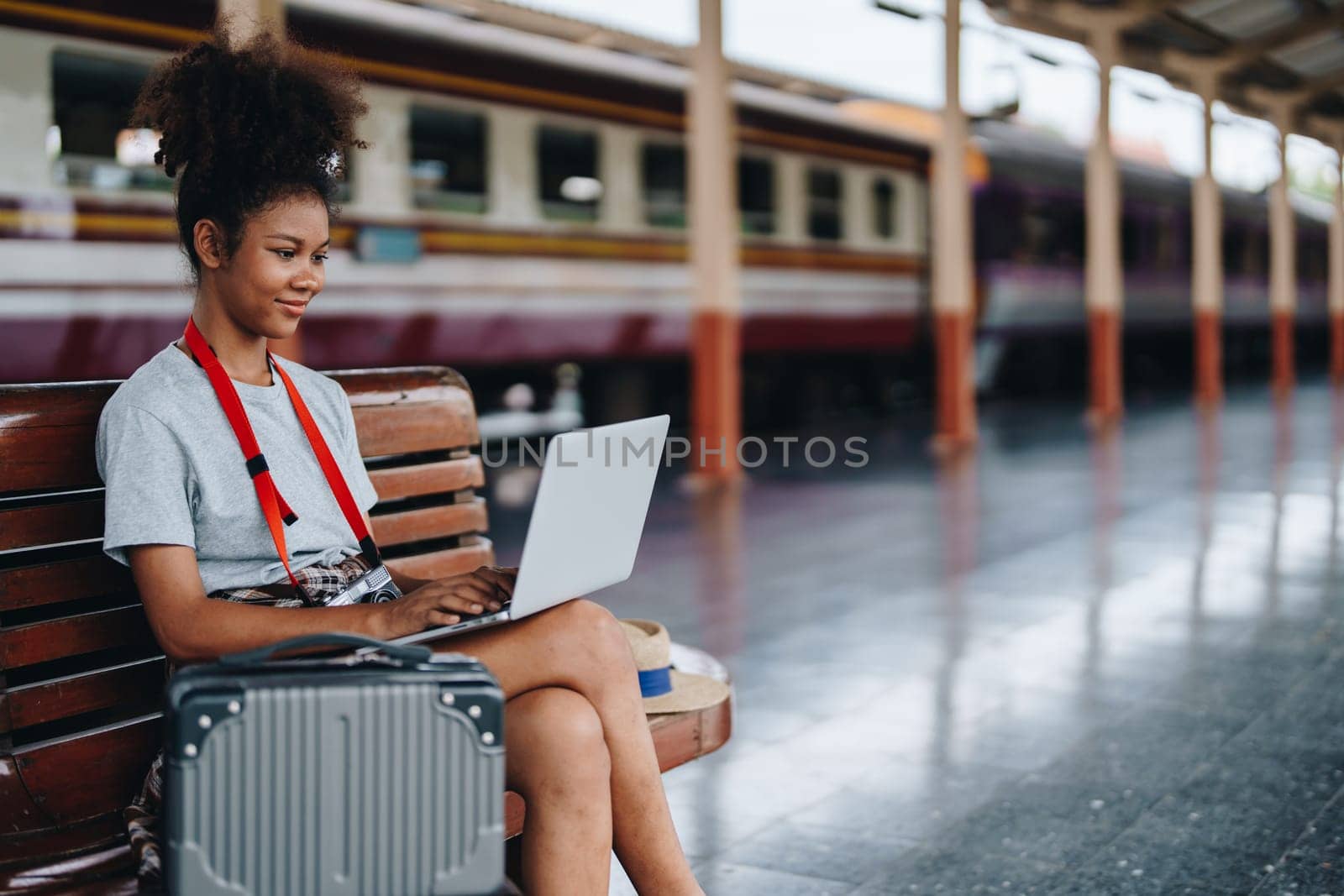 Asian teenage girl african american traveling using computer laptop while waiting for a train at a station