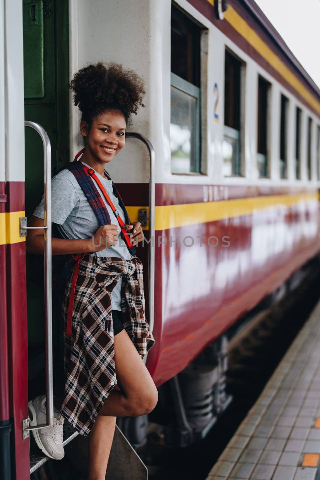 Tourists african american are showing happy expressions while waiting for their journey in the train station. by Manastrong