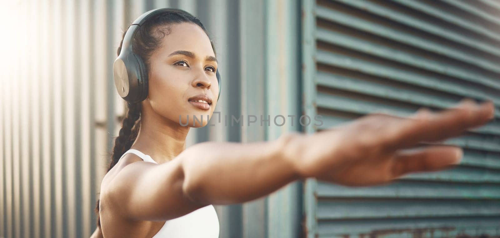 Fitness, workout and woman stretching arms in city listening to music, audio and track. Sports, healthy body and female person outdoors with headphones for exercise, training and warm up for running.