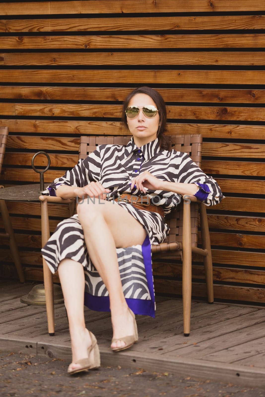 Beautiful girl relaxing on a resort. Woman in zebra dress sitting on chair by sarymsakov