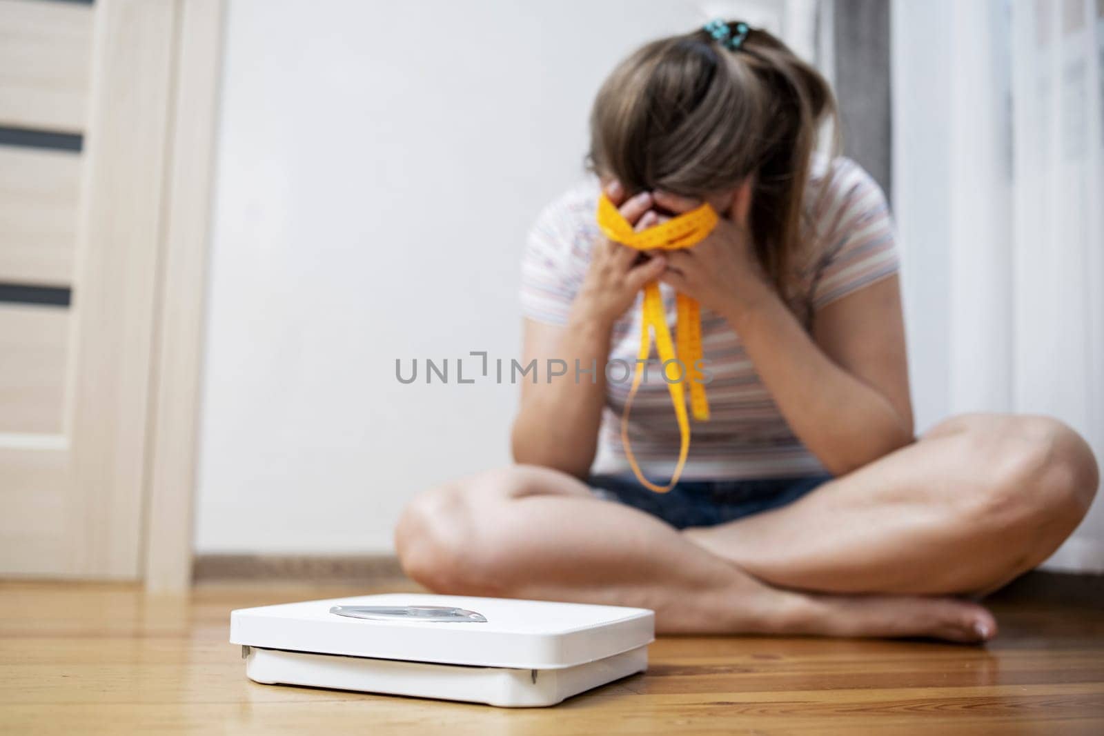 White scale and depression, upset and sad woman with measuring tape on wooden floor.