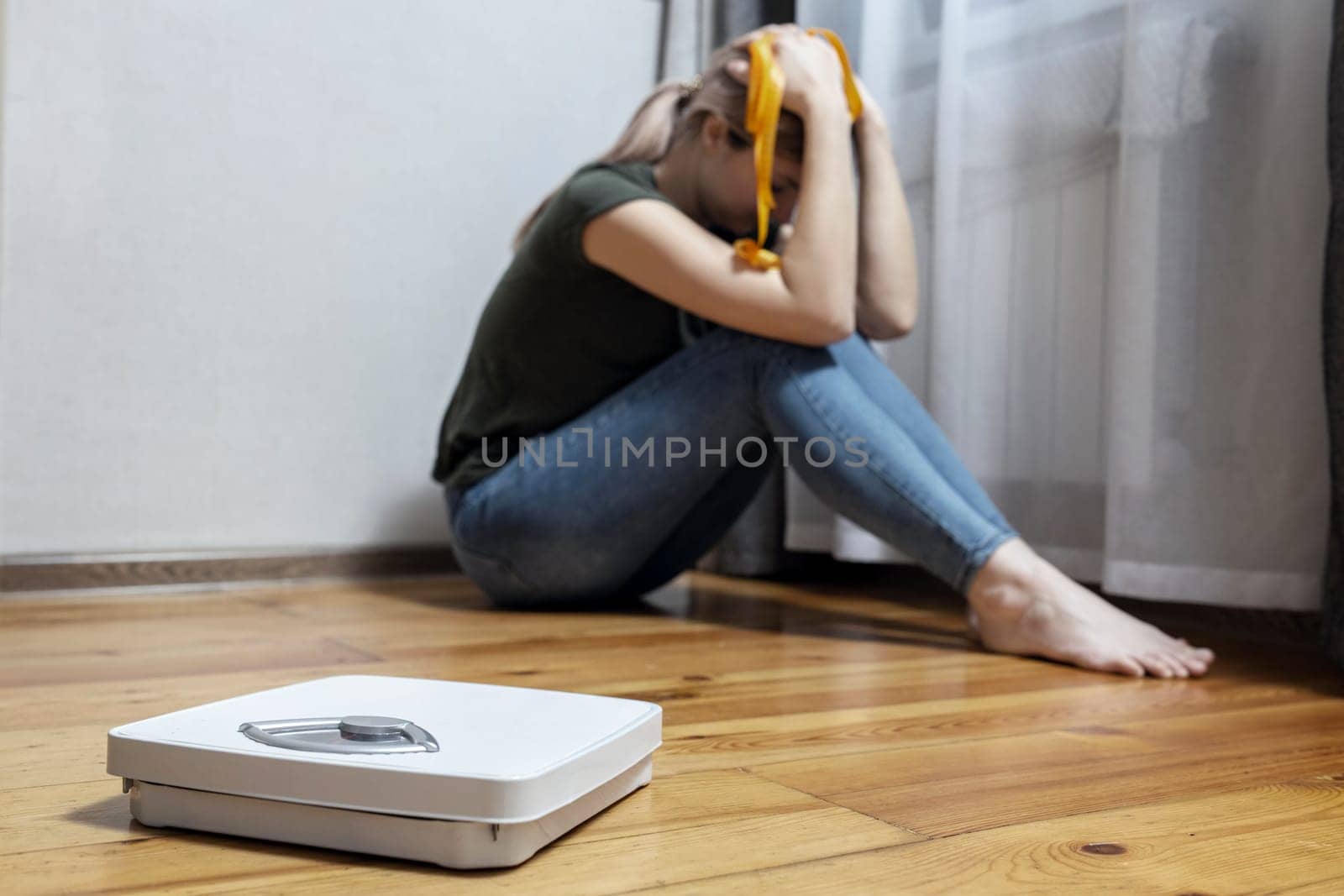 White scale and depression, upset and sad woman with measuring tape on wooden floor.