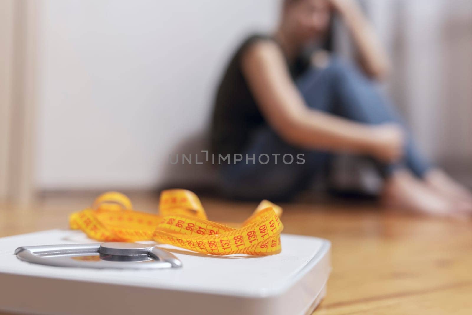 White scale and depression, upset and sad woman with measuring tape on wooden floor.