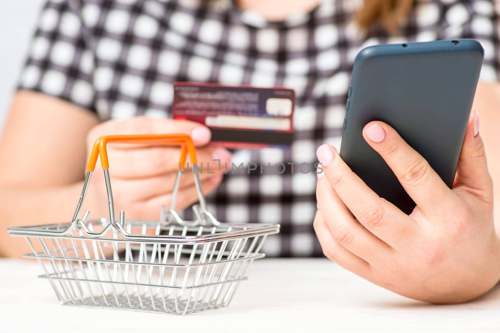 A woman holding plastic credit card and phone, making secure internet payment. A female customer shopping online.
