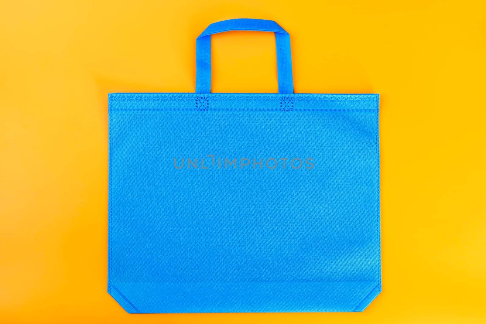 The blue shopping bag on a yellow background. Mockup for design. Shopping and sale concept.