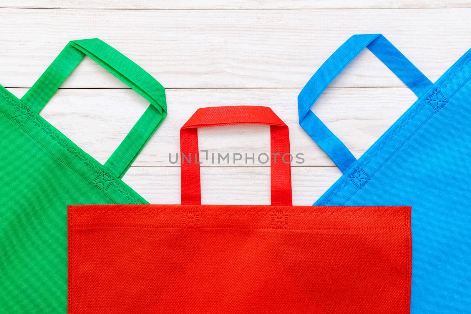 Colorful shopping bags on white wooden background. Mockup for design. Shopping and sale concept.