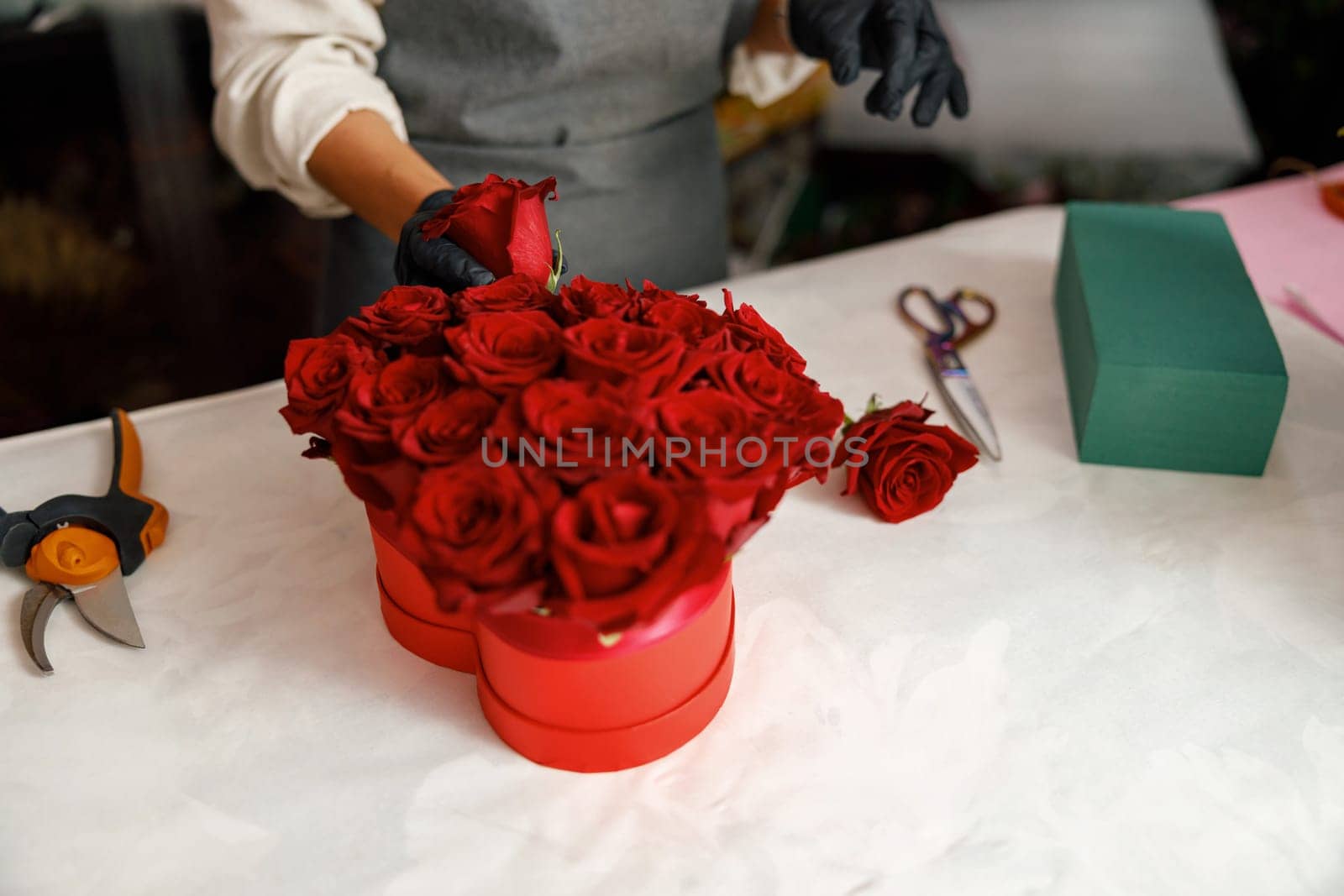 Close up of florist in flower shop make roses compositions for holiday. Family flower's business by Yaroslav_astakhov