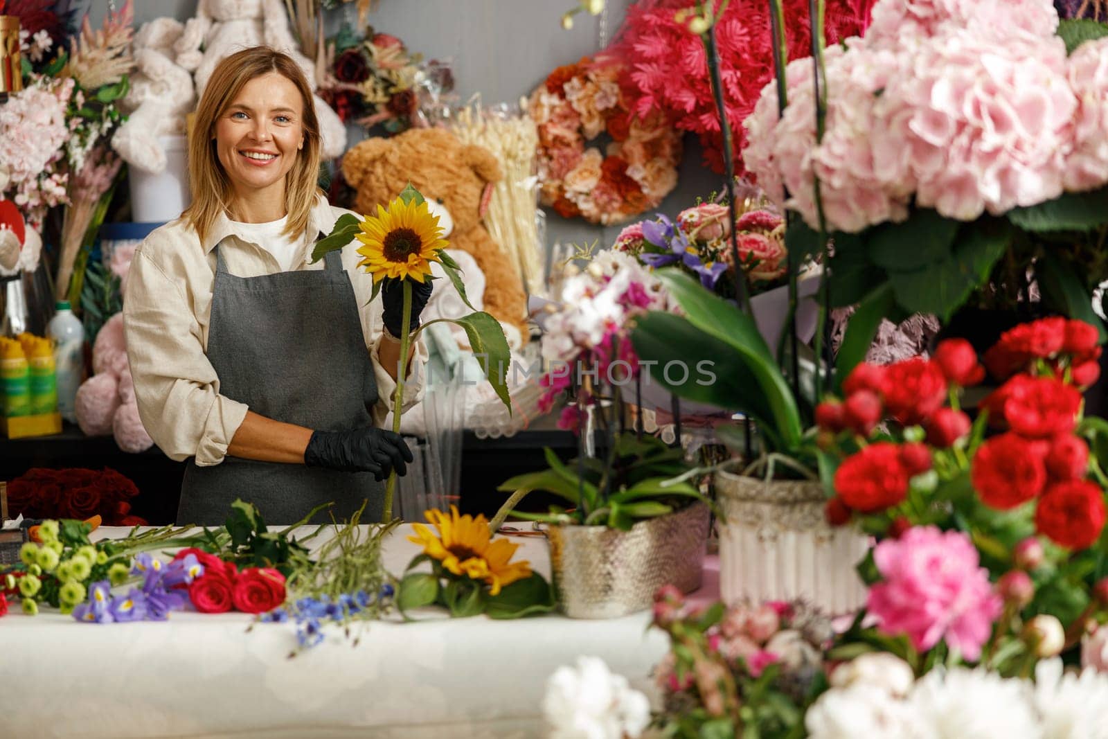 Female decorator creating beautiful bouquet at table. Lifestyle flower shop