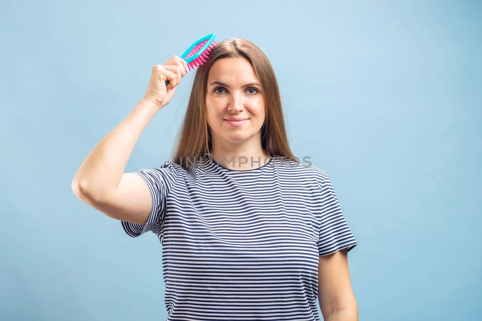 Young beautiful brunette woman brushing her long healthy hair. Haircare concept.