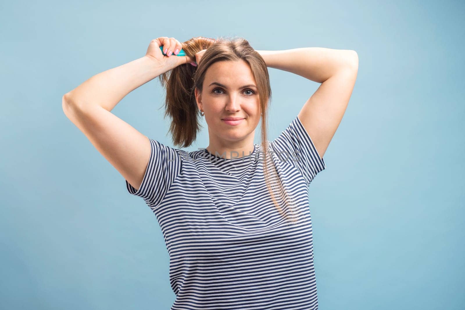 Young beautiful brunette woman brushing her long healthy hair. Haircare concept.