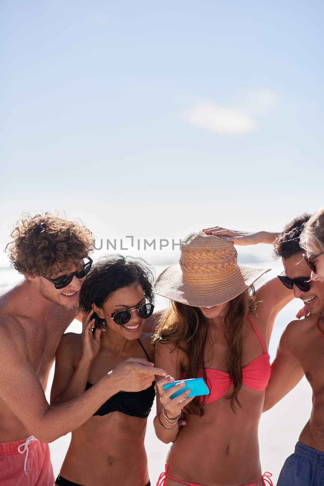 Social media, freedom and friends on the beach with a phone to post a status update while on vacation together. Mobile, summer and a group of young people outdoor in nature for holiday travel by YuriArcurs