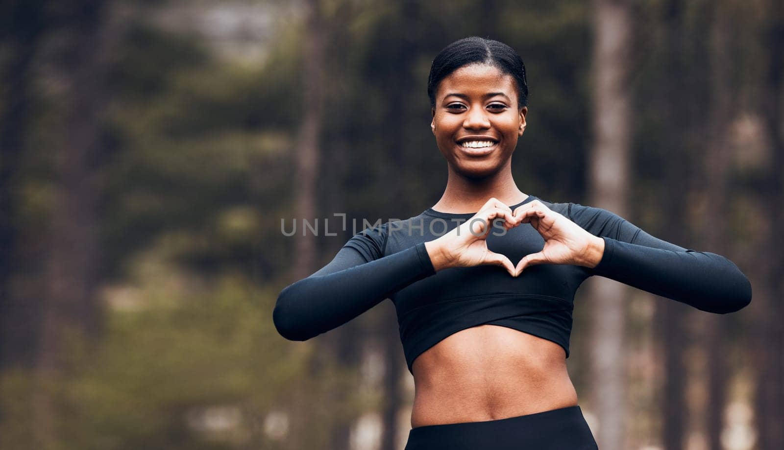 Heart hand, black woman and fitness in nature with exercise and fitness with love gesture. Sport, female person and support outdoor by the trees after a run with romance sign from a workout in park.
