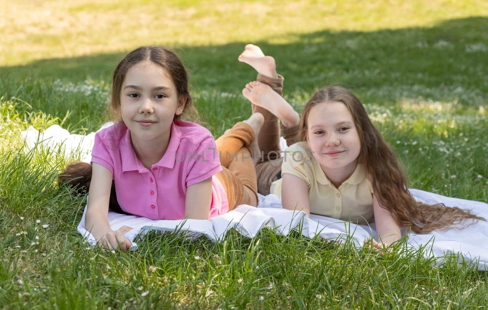 Joyful Little Children Enjoys Summer Time, School Break Lying On Grass In Meadow, Park At Sunny Day. Siblings Love, Having Fun In Nature. True Friendship. Horizontal Plane. by netatsi