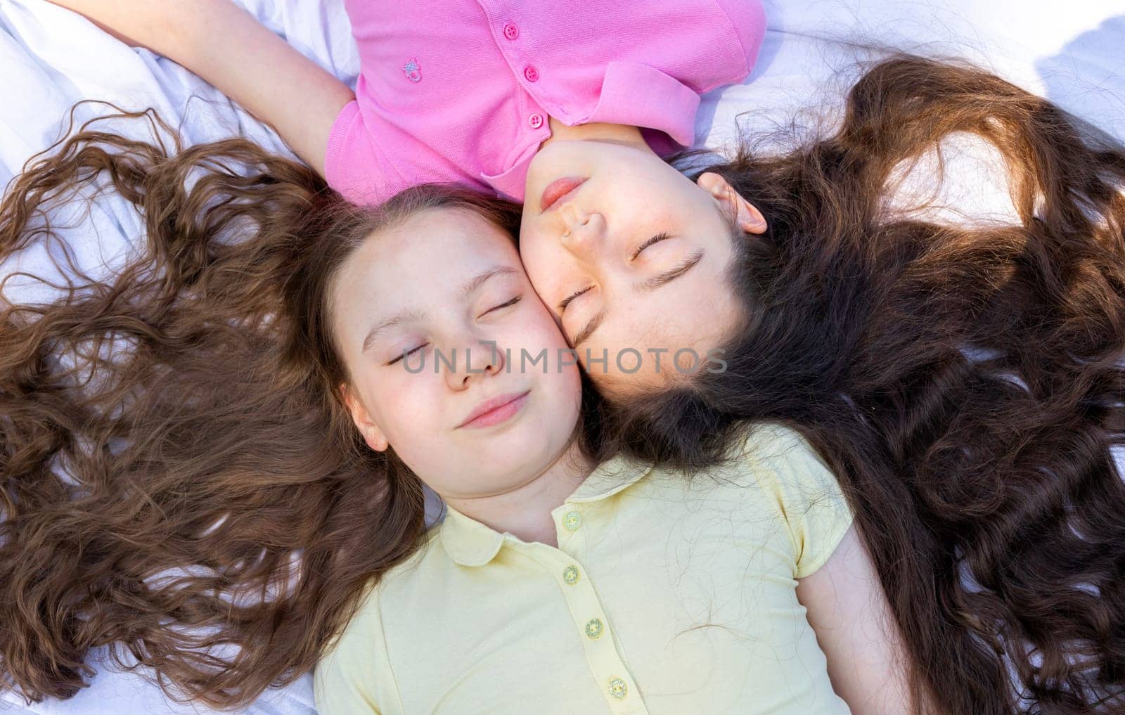 Top View Little Girls Lying On Plaid In Park, Meadow Under Sun, School Break Siblings Friendship, Having Fun In Nature. Horizontal Plane. by netatsi