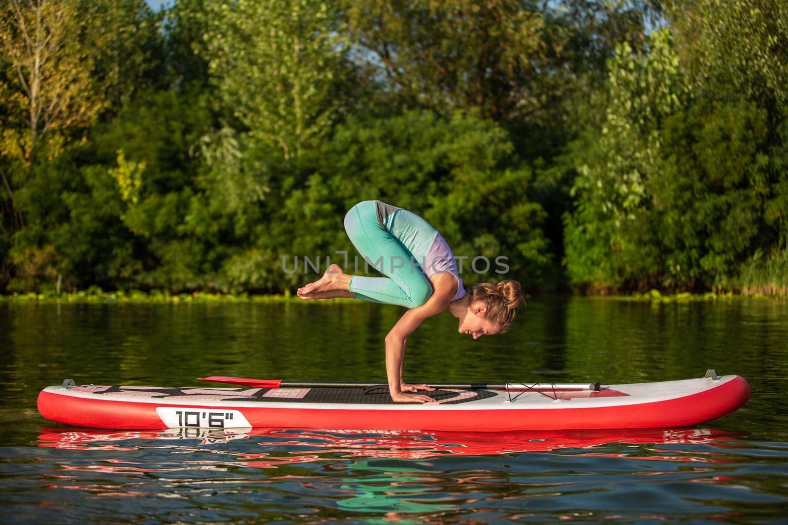 Young woman are doing yoga on a stand up paddle board SUP on a beautiful lake or river. The concept of a healthy lifestyle. Sport. Yoga. Hobby