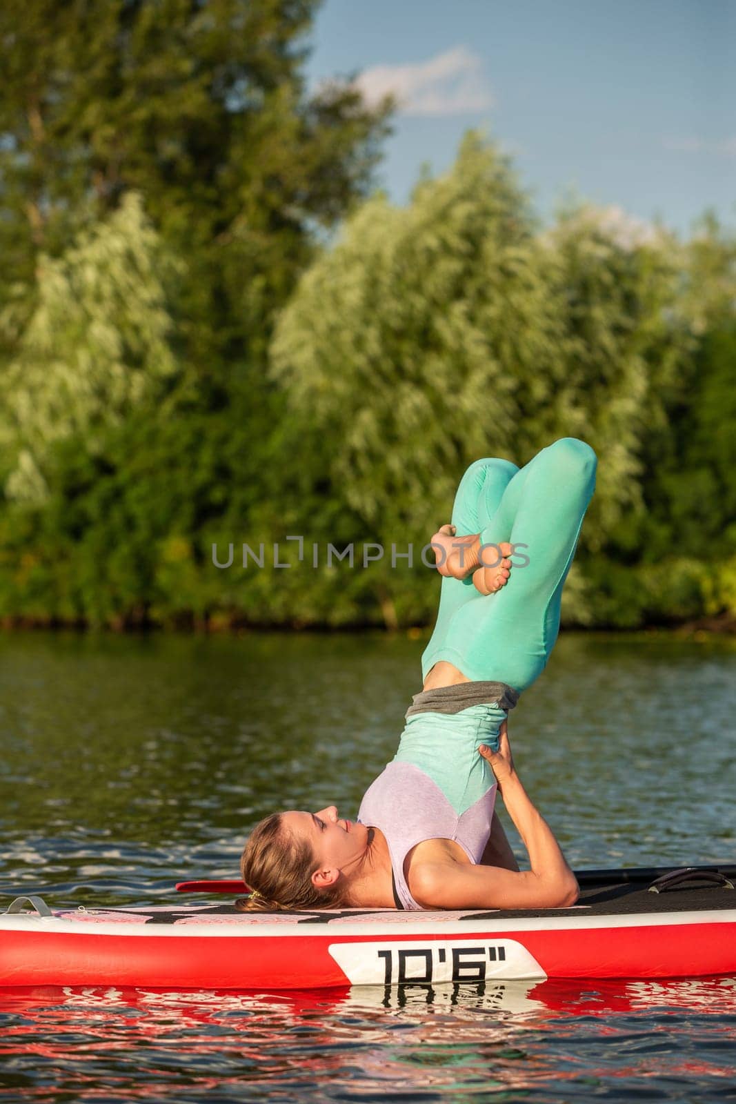 Woman practicing yoga on the paddle board in the morning. Sport. Hobby. Yoga.
