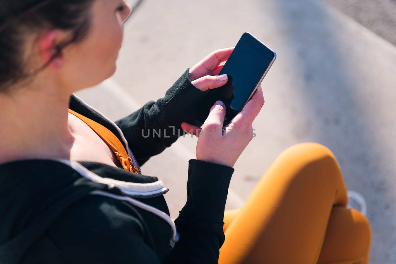 close up top view of an unrecognizable sportive woman using a mobile phone, concept of technology of communication and urban sports