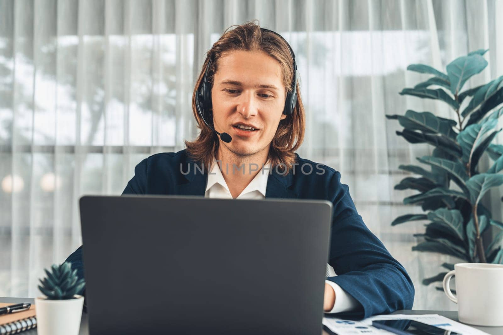Male customer service operator or telesales agent sitting at desk in office, wearing headset and engage in conversation with client to provide support or close sales. Call center portrait. Entity