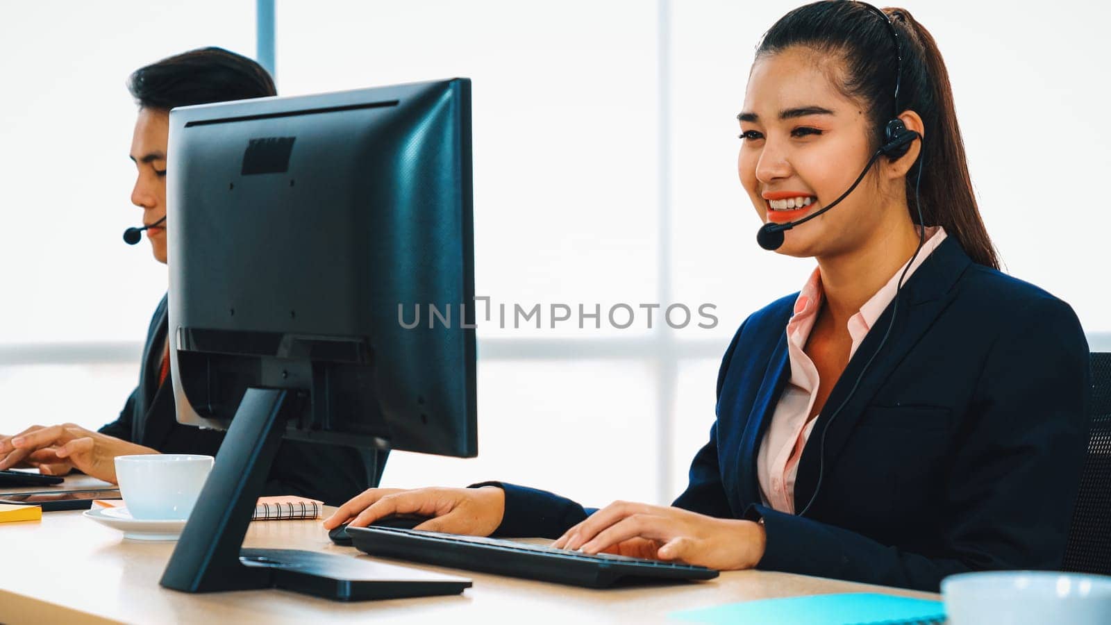 Business people wearing headset working in office to support remote customer or colleague. Call center, telemarketing, customer support agent provide service on telephone video conference call. Jivy