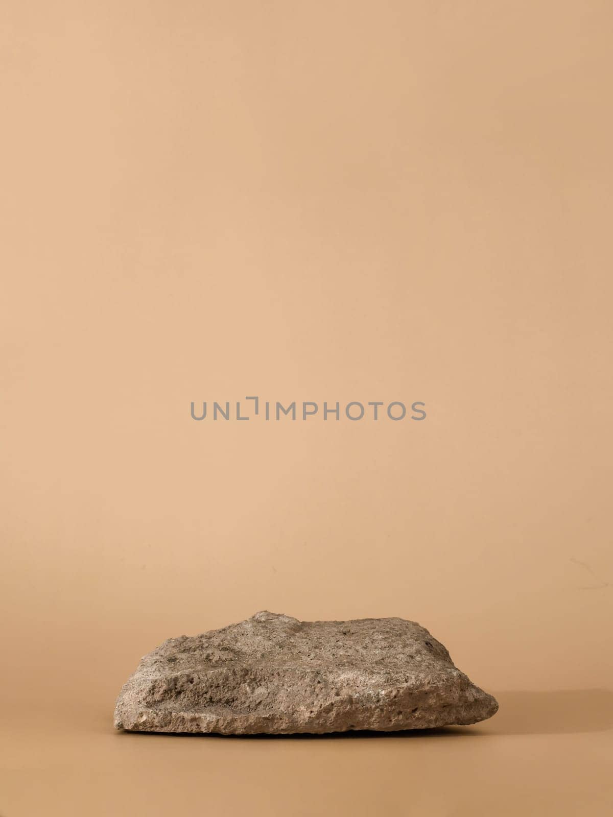 Mockup geometric shape natural rock podium. Stone shape on pastel light beige background. Can use as perfume and cosmetic mock up. Copy space. Vertical