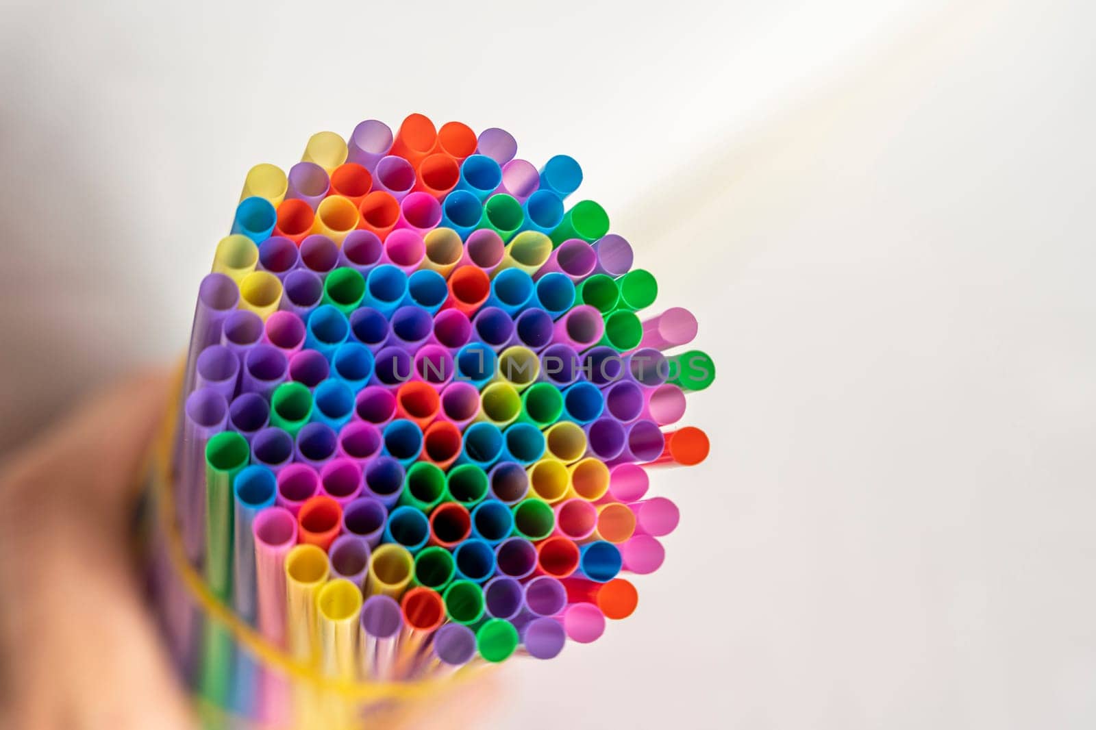 a lot of bright multicolored cocktail tubes are clutched in the bartender's hand. Multicolored Plastic Cocktail Tubes