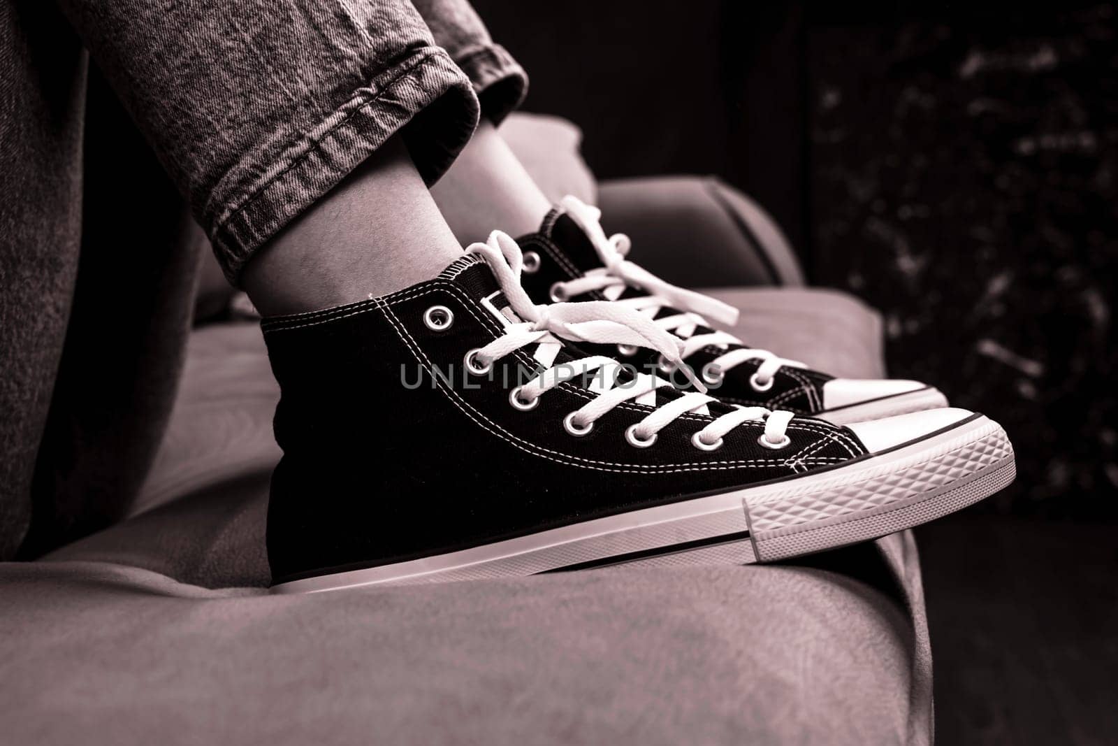 Teenager's feet in casual new sneakers on the sofa by audiznam2609