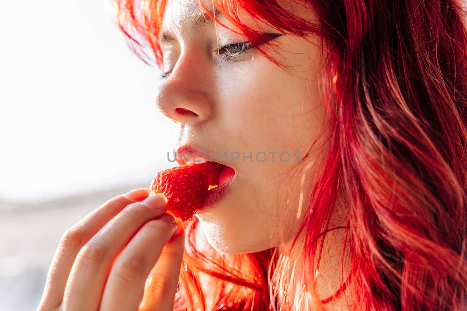 cute girl with red hair eats delicious ripe strawberries close-up. delicious and healthy vitamins and diet and dessert