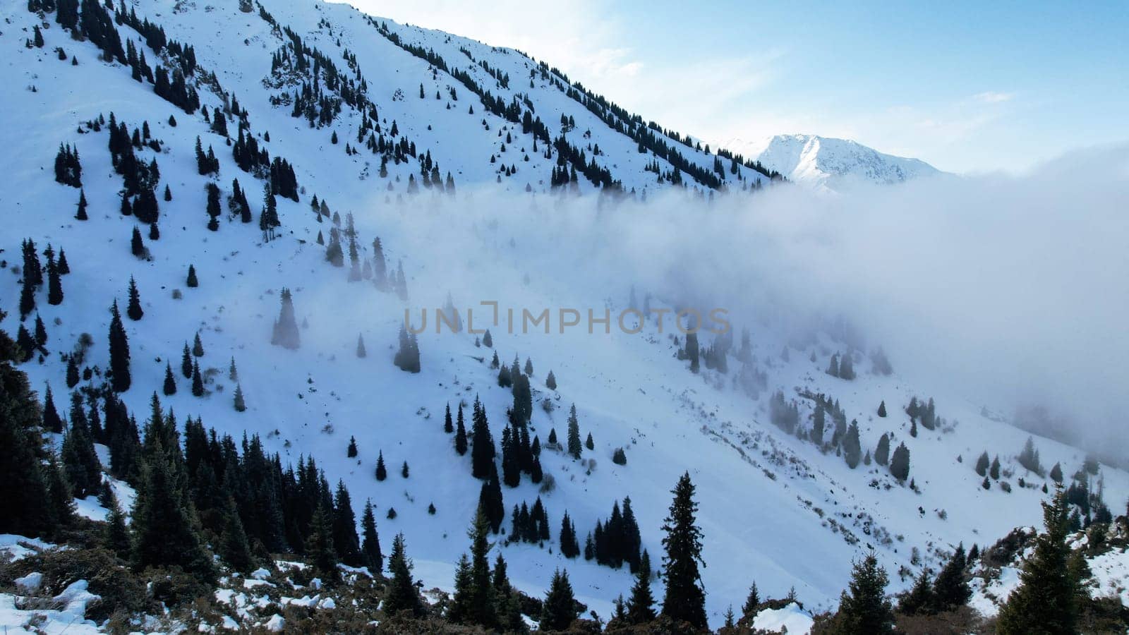 White cumulus clouds in snowy mountains in winter by Passcal