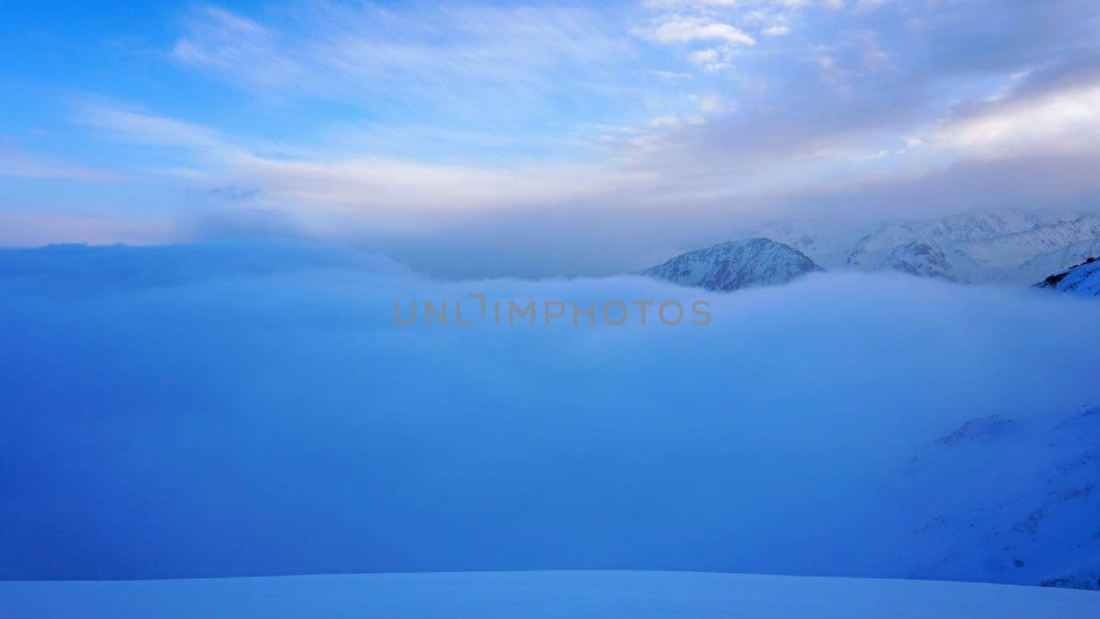 Ocean of clouds in snowy mountains at dawn by Passcal