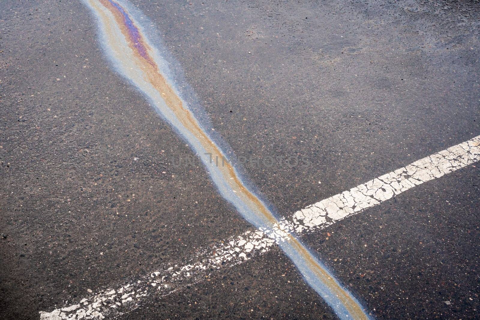 After rain on wet pavement, an iridescent spill of oil or gasoline crosses the dividing line.