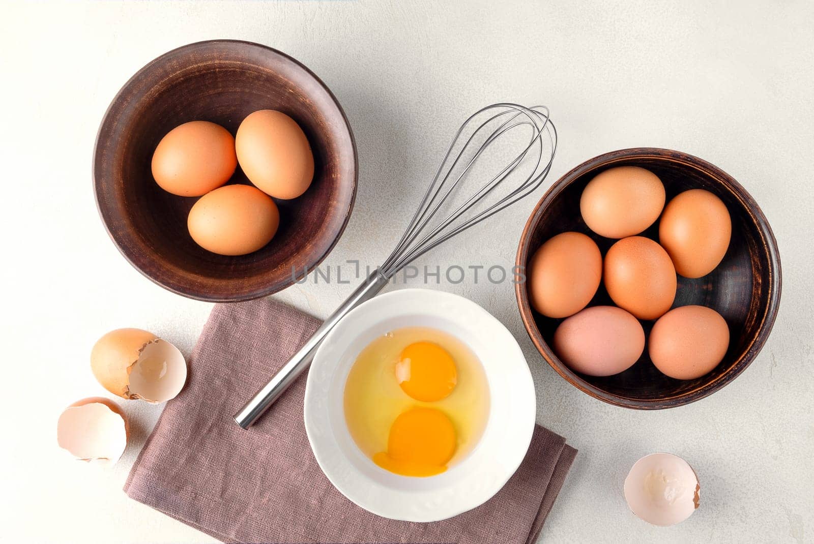 Top view brown chicken eggs in a bowl on the table with a whisk to beat the eggs.