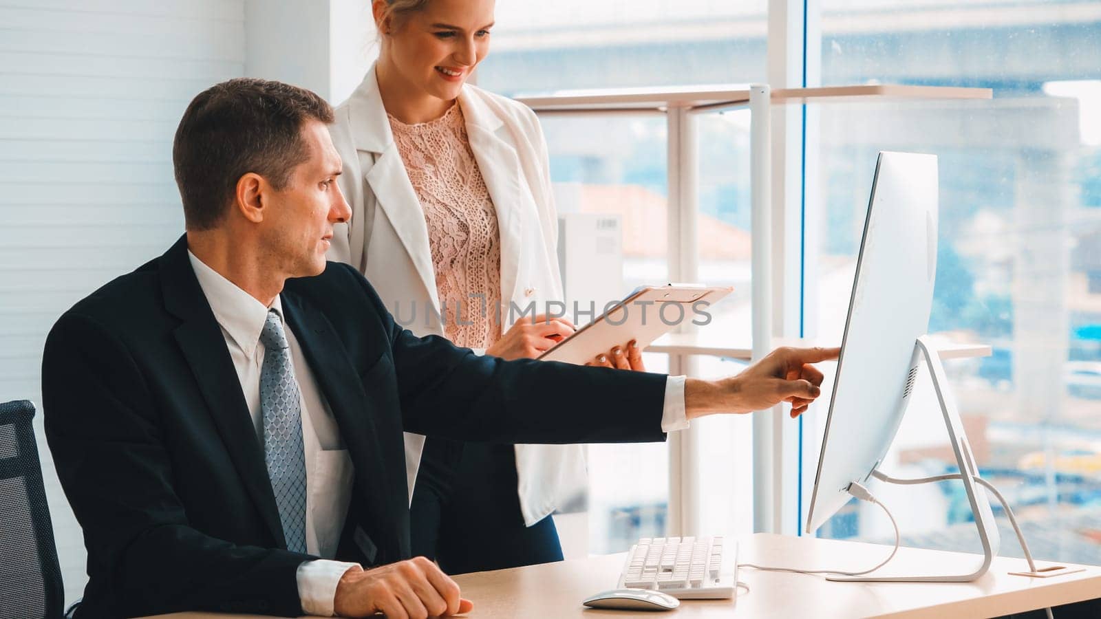 Two business people talk project strategy at office meeting room. Businessman discuss project planning with colleague at modern workplace while having conversation and advice on financial report. Jivy