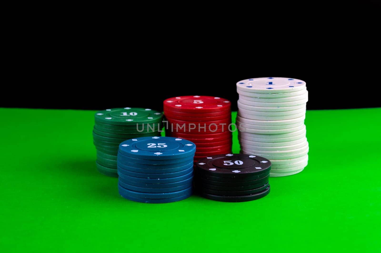 Poker game, stacks of chips on a poker table on a black background. Stacks of chips on a green poker table on a black background.