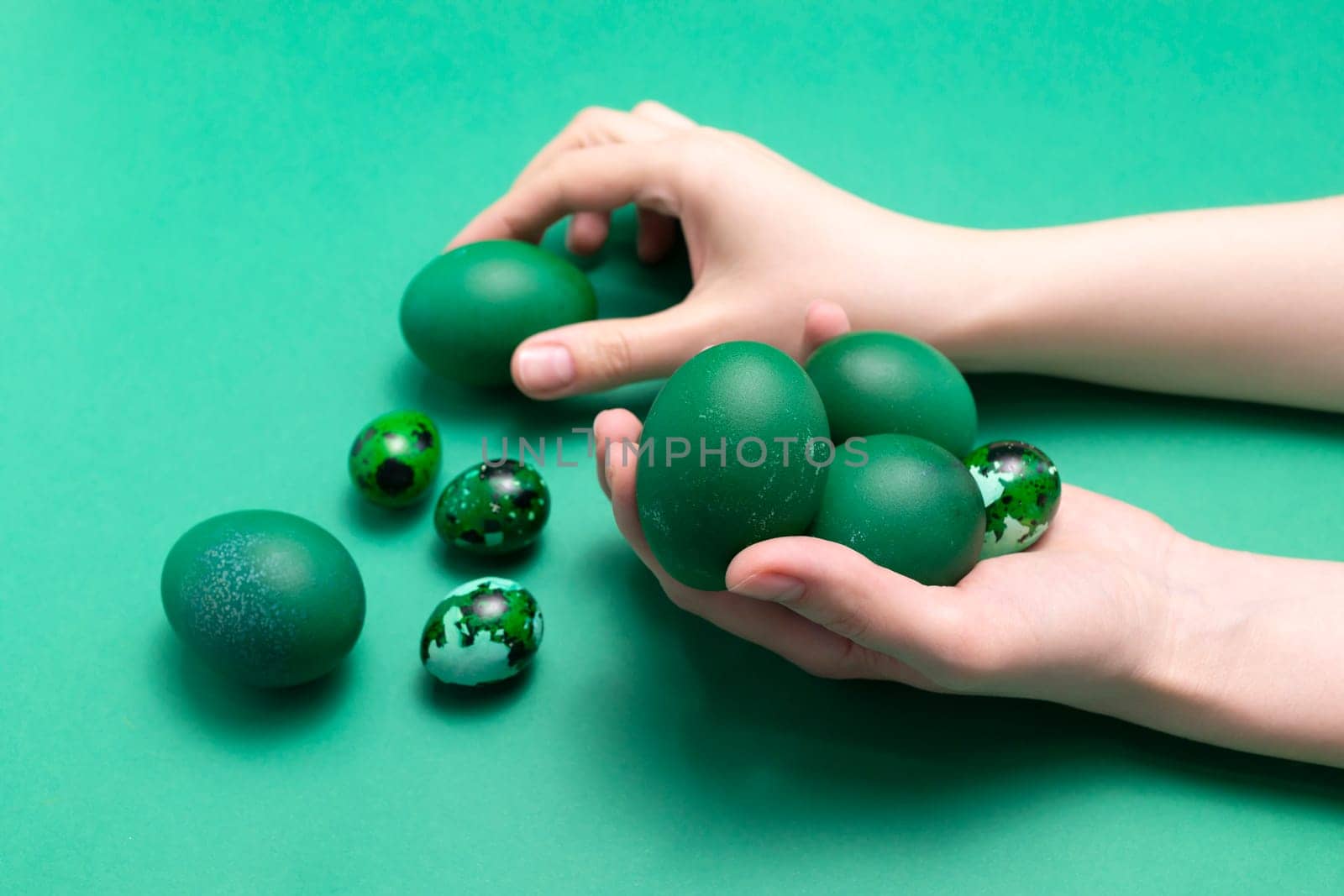 Female hands holding blue green Easter chicken quail eggs on blue background. Pascha or Resurrection Sunday, Christian festival and cultural holiday concept. Monochromatic. Closeup,Horizontal plane by netatsi