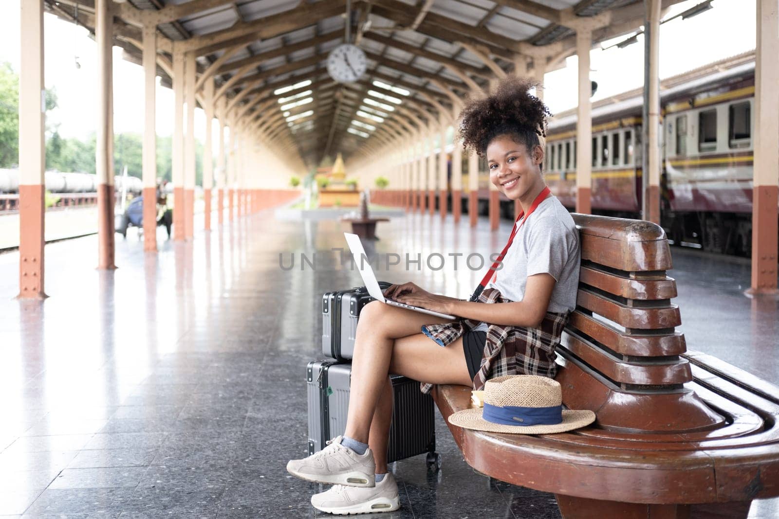 Young woman girl female sitting use computer laptop and travel bag suit case on the floor at station by wuttichaicci