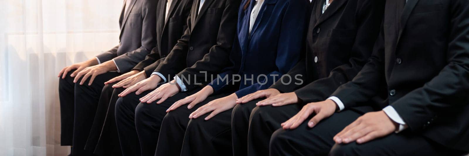 Asian job applicant waiting in line with good manners hand gesture and identical black formal wear for job interview. Modern and professional job seeker concept. Trailblazing