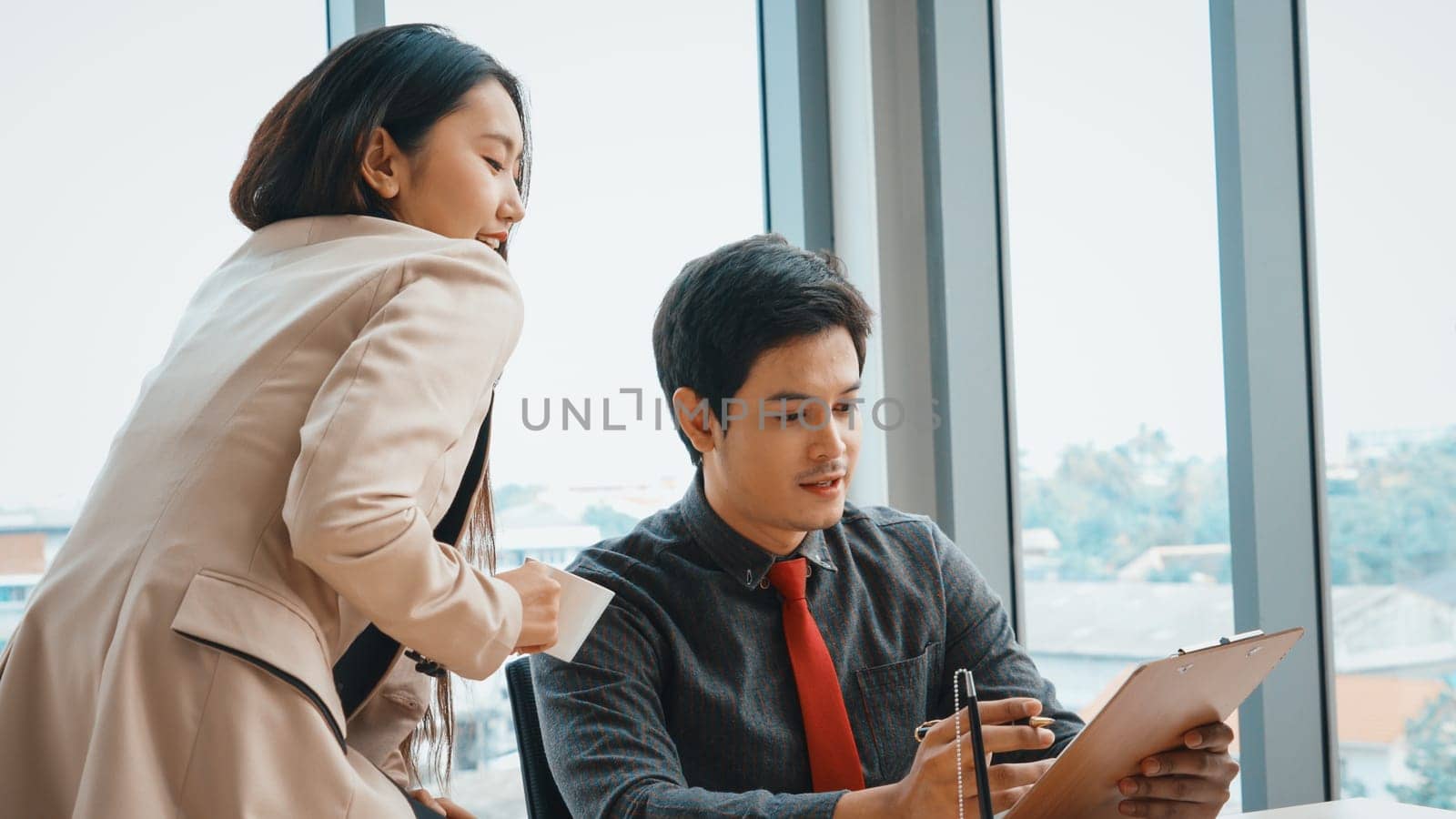 Two business people talk project strategy at office meeting room. Businessman discuss project planning with colleague at modern workplace while having conversation and advice on financial report. Jivy