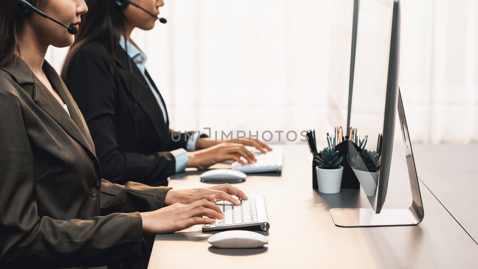 Panorama call center operator team or telesales representative siting at office desk wearing headset and engaged in conversation with client providing customer service support or making sales. Prodigy