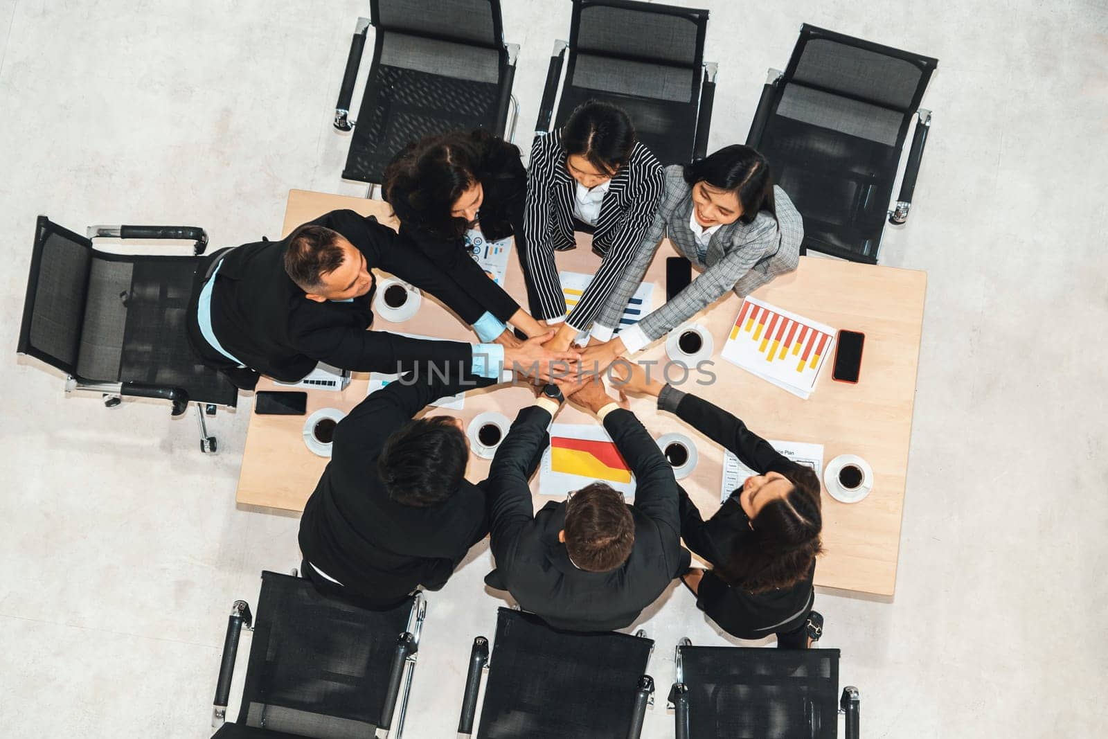 Happy business people celebrate teamwork success together with joy at office table shot from top view . Young businessman and businesswoman workers express cheerful victory show unity support . Jivy