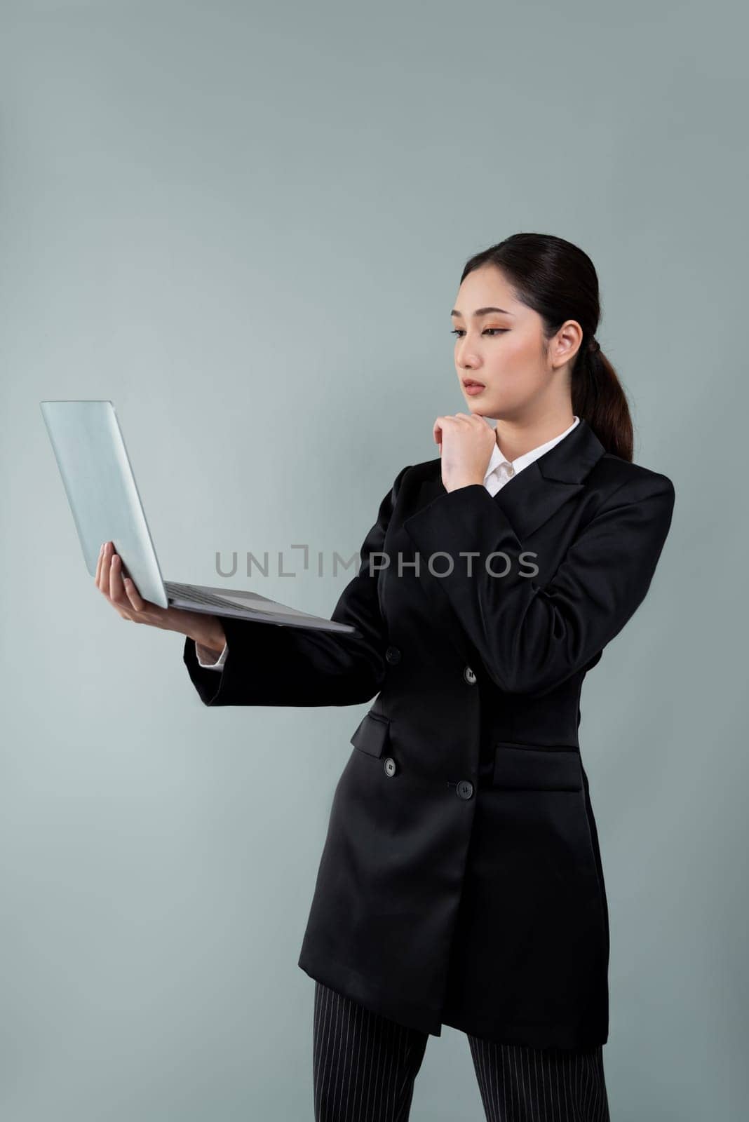 Businesswoman with laptop stands on isolated background. Enthusiastic by biancoblue