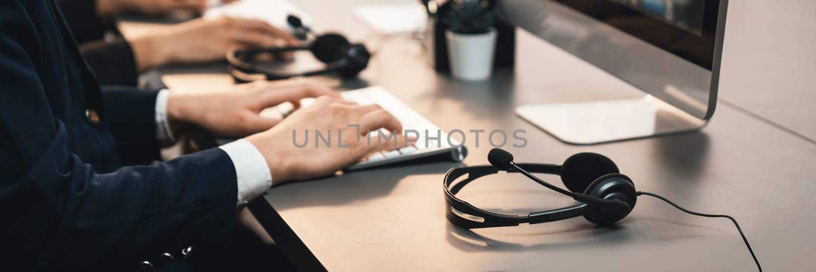 Panorama focus headset on call center workspace desk with blur background of operator team or telesales representative engage in providing client with customer support service or making sales. Prodigy