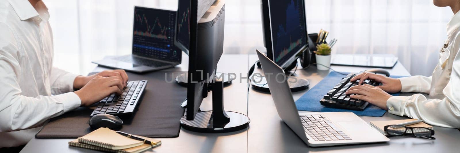 Group of traders discussing on office desk, monitoring stock market on monitor at office workplace. Businessman and broker analyzing stock graph together at stock trading company. Trailblazing