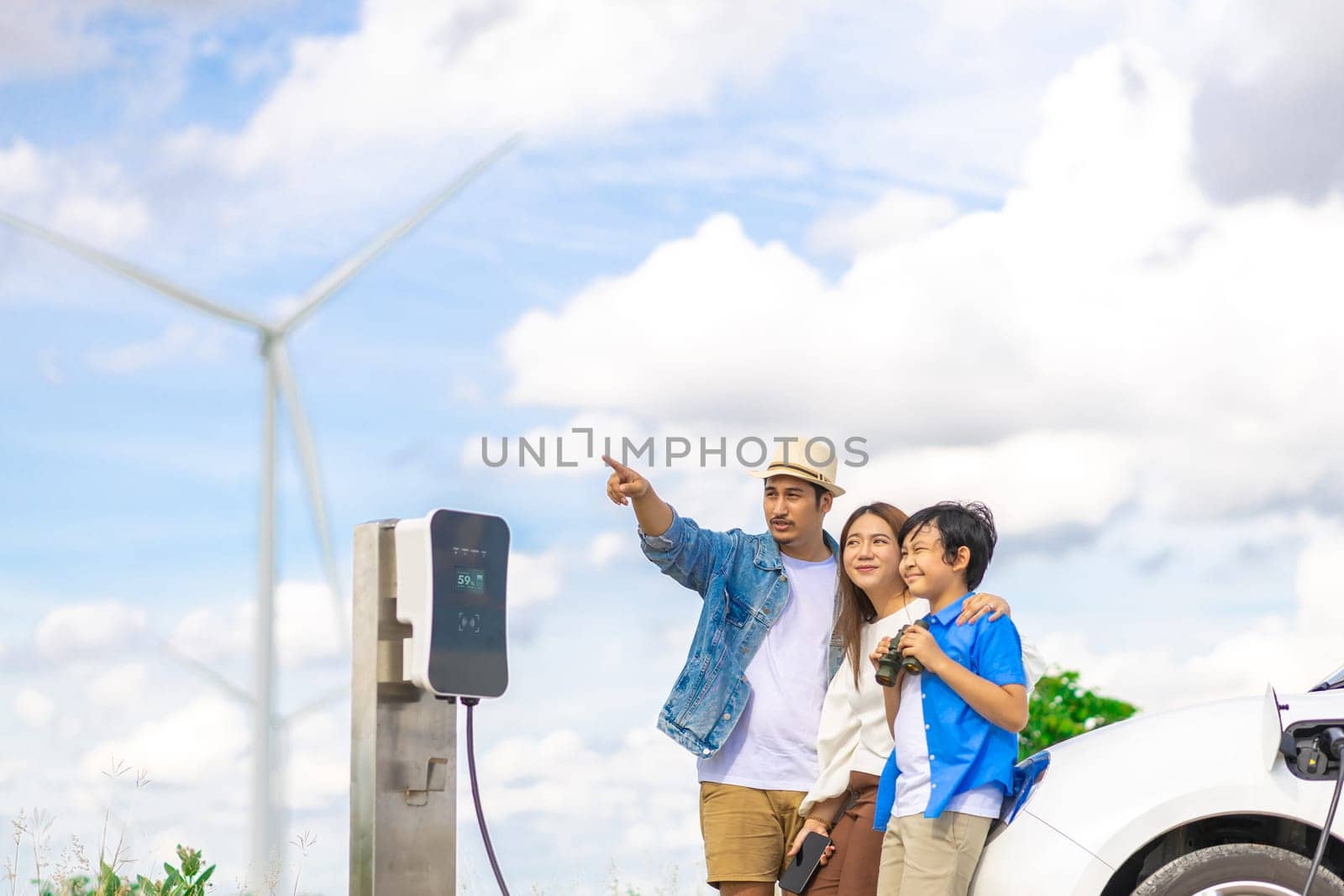 Concept of progressive happy family at wind farm with electric vehicle. by biancoblue