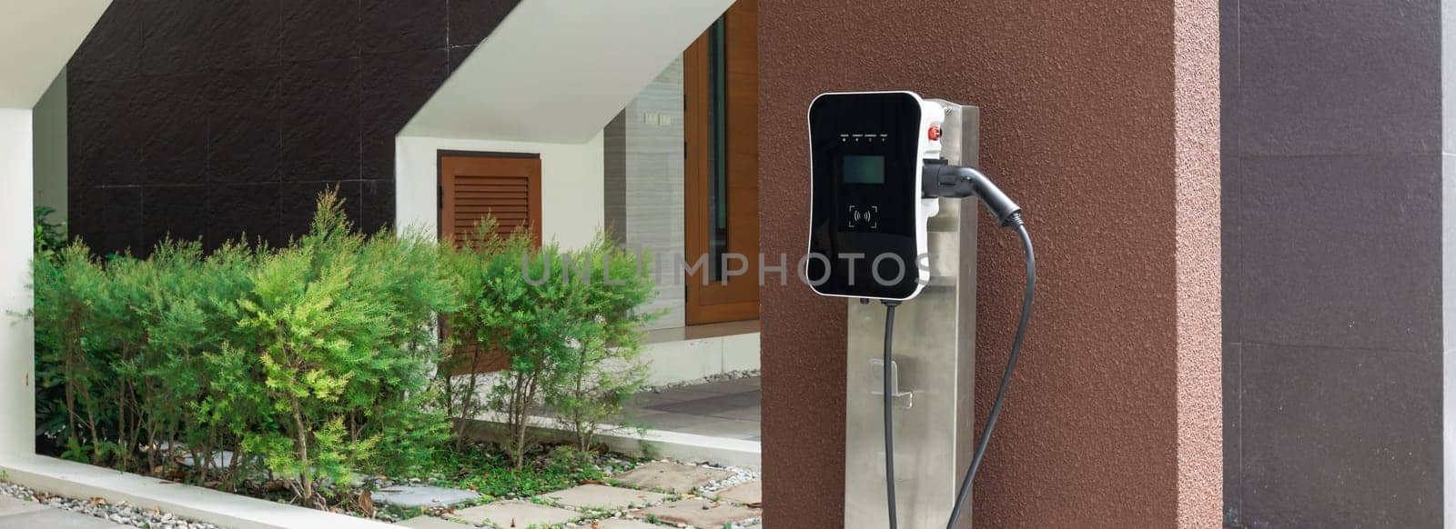 Progressive green energy-powered charging station concept for electric vehicle connected to home charging station at the garage or backyard. Eco friendly rechargeable car powered by clean energy.